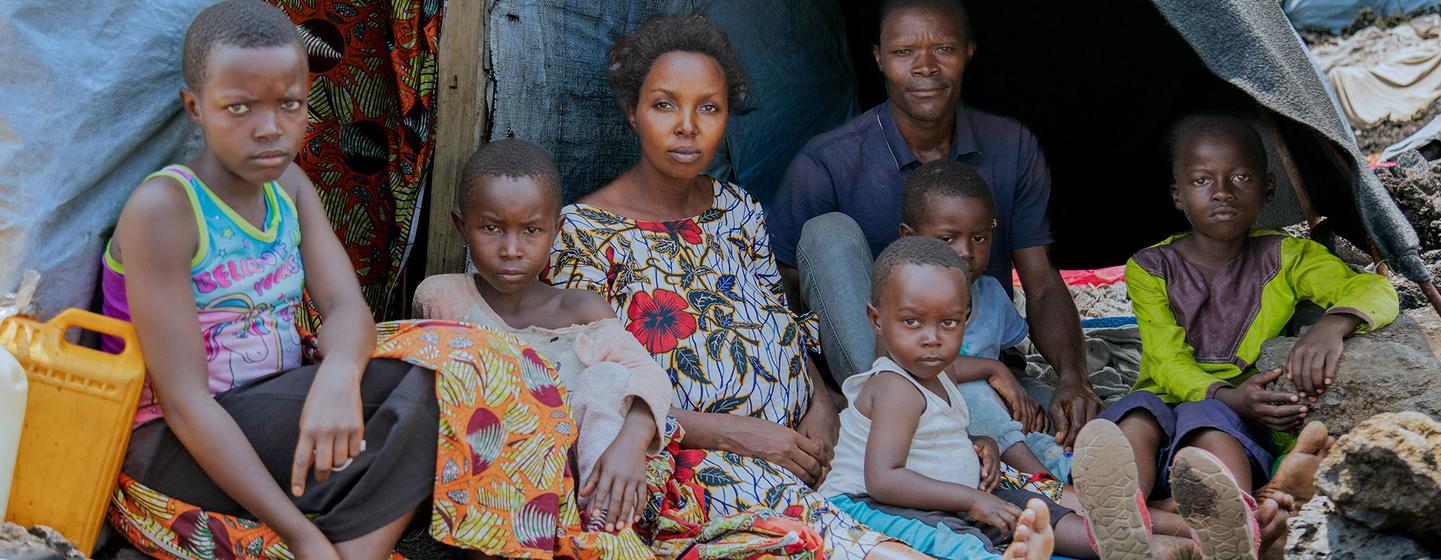 Ombeni, su marido y sus hijos se reúnen fuera de su refugio improvisado en un lugar de desplazados al oeste de Goma tras huir de la violencia.