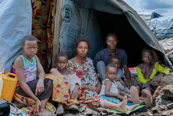 Ombeni, her husband, and their children gather outside their makeshift shelter at a displacement site west of Goma after fleeing violence.