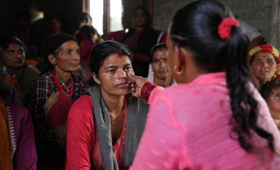 A female community health volunteer screens a woman in rural nepal for anaemia by checking the lower eyelid for a pale colour.
