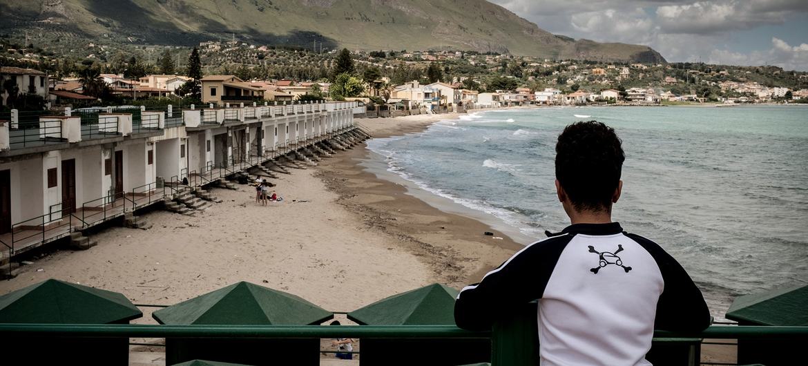 A young migrant boy looks across a bay in Italy.