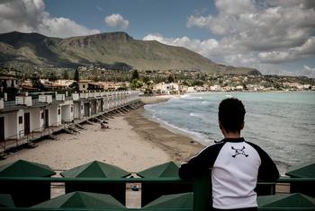 在意大利，一名年轻的移民男孩眺望海湾对岸。