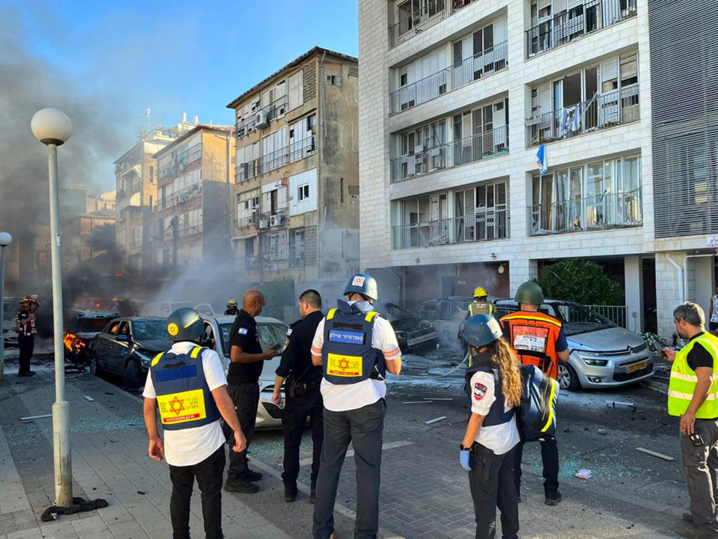 Des secouristes israéliens dans une rue gravement endommagée par les tirs