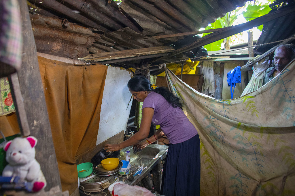 Minabige, 49 ans, vit avec son mari et sa fille dans une petite cabane d'une pièce au Sri Lanka, où ils mangent, cuisinent, prient, étudient et dorment, à quelques centimètres d'un égout à ciel ouvert.