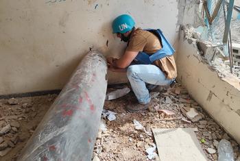 موظف من دائرة الأمم المتحدة للإجراءات المتعلقة بالألغام (أونماس) يفحص صاروخا غير منفجر في مدرسة في خان يونس. 