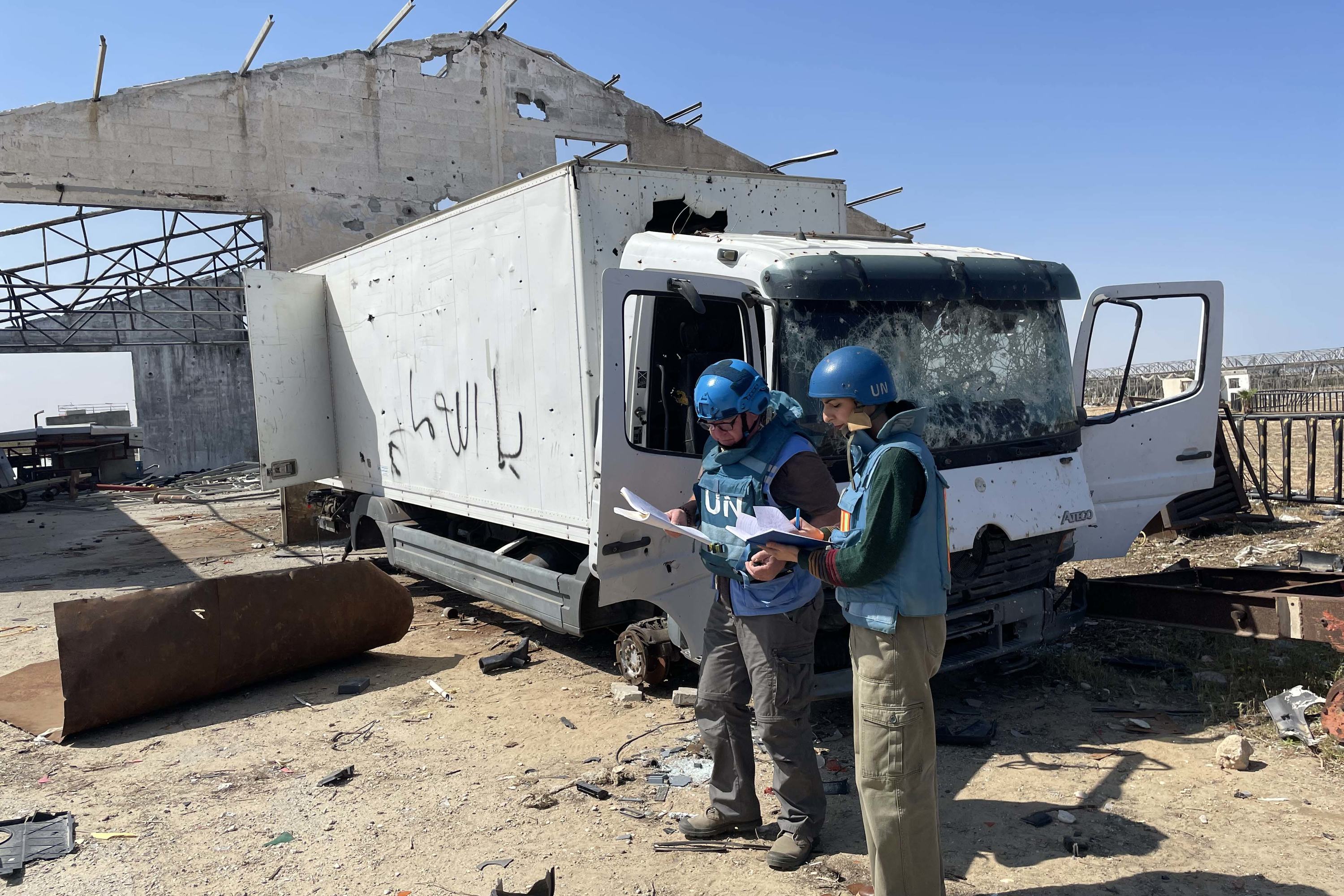 يقوم اثنان من ضباط دائرة United Nations للأعمال المتعلقة بالألغام (UNMAS) مرتدين معدات واقية بتفتيش شاحنة متضررة في خان يونس، غزة.