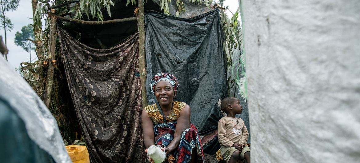 Clémence Ndabohweje, 49, washes dishes in front of the tent in which she has taken refuge with her six children and three grandchildren at an IDP site in eastern DR Congo. The family fled their village in Rutshuru territory following clashes. 