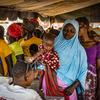 Mulheres fazem fila para receber cartões de beneficiários para comprar farinha fortificada para prevenir a desnutrição em Kongoussi, Burkina Faso