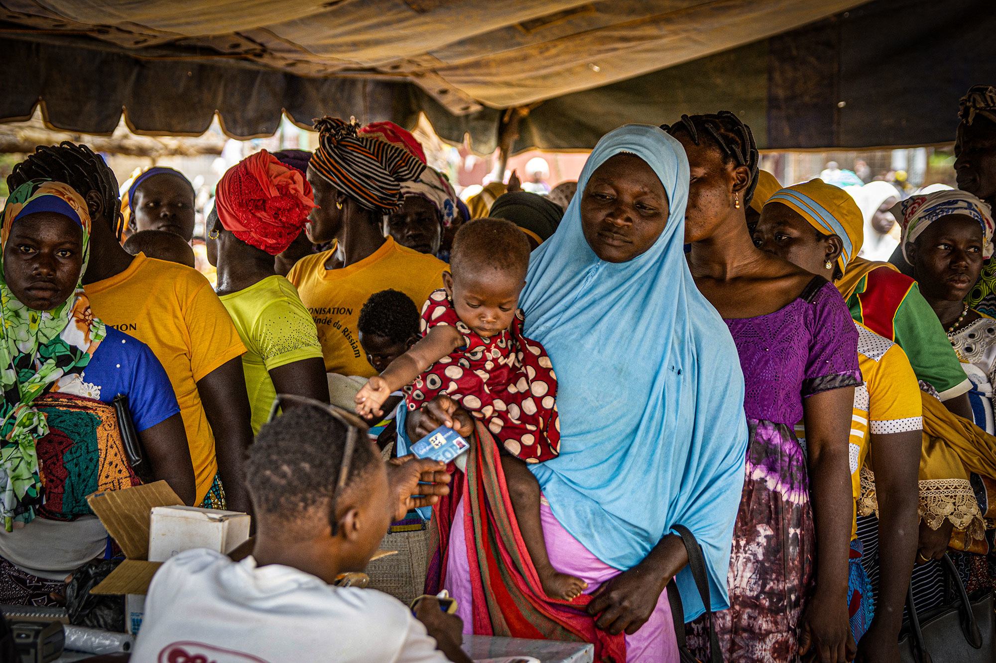 نساء يصطفن للحصول على بطاقات المستفيدين لشراء الدقيق المدعم للوقاية من سوء التغذية في كونغوسي، بوركينا فاسو.