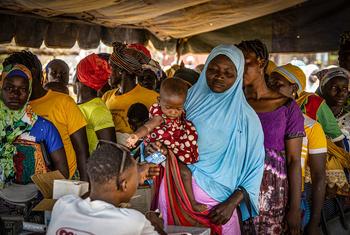 Mulheres fazem fila para receber cartões de beneficiários para comprar farinha fortificada para prevenir a desnutrição em Kongoussi, Burkina Faso