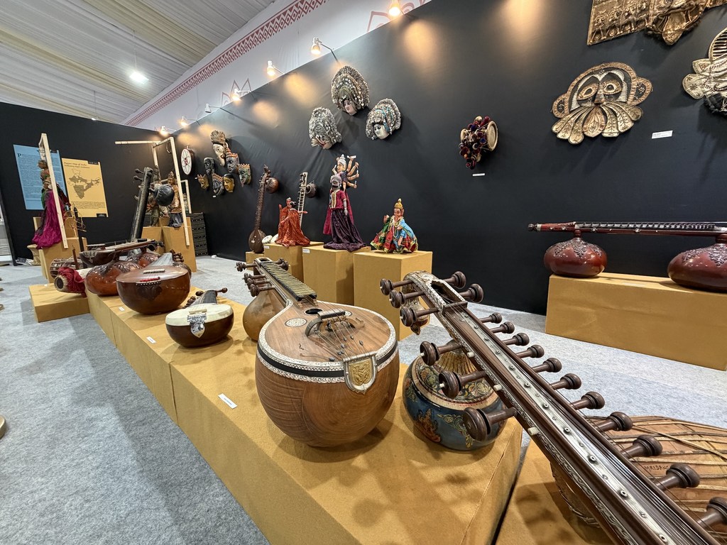 भारत में UNESCO की अमूर्त सांस्कृतिक विरासत सम्मेलन में पारंपरिक भारतीय संगीत वाद्ययंत्रों और सजावटी मुखौटों की प्रदर्शनी।