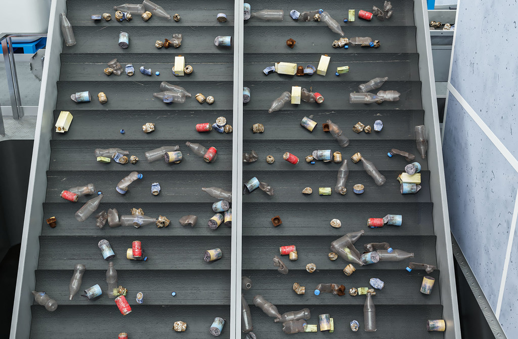 Des bouteilles en plastique et des bouchons sur un convoyeur dans une usine de recyclage.