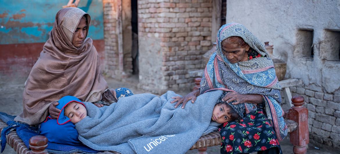 Bibi wawili wakiwapa joto wajukuu wao kwa blanketi ziliyotolewa na UNICEF katika mkoa wa Sindh, Pakistan.