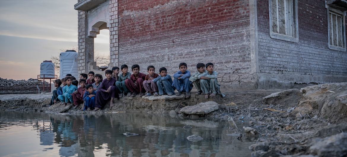 पाकिस्तान के सिन्ध प्रान्त में 2022 में आई भीषण बाढ़ के दूषित पानी के तालाब के पास बैठे बच्चे.