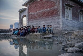 पाकिस्तान के सिन्ध प्रान्त में 2022 में आई भीषण बाढ़ के दूषित पानी के तालाब के पास बैठे बच्चे.