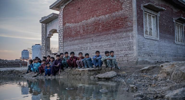 Дети сидят у пруда с загрязненной паводковой водой в провинции Синд, Пакистан.