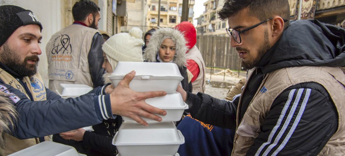 Pessoas afetadas pelo terremoto em Aleppo, na Síria, recebem refeições quentes distribuídas pelo Programa Alimentar Mundial.