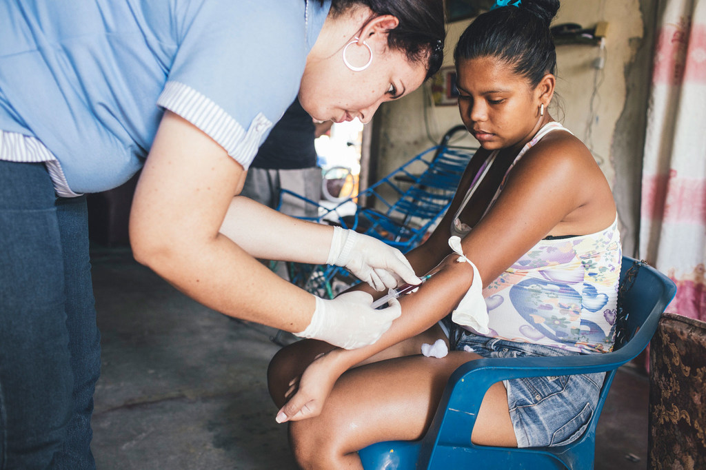 Una trabajadora sanitaria toma muestras de sangre a una mujer que había estado previamente enferma de dengue (archivo).