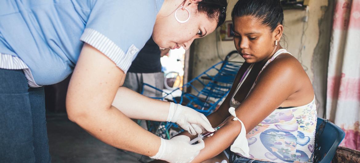 Um profissional de saúde coleta amostras de sangue de uma mulher que já havia contraído dengue