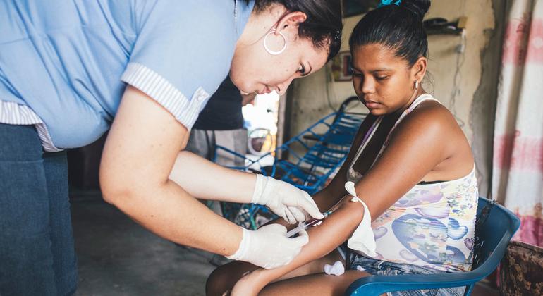 Um profissional de saúde coleta amostras de sangue de uma mulher que já havia contraído dengue. (arquivo)