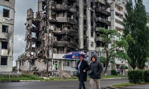 Duas pessoas passam por um quarteirão residencial destruído na região de Kiev