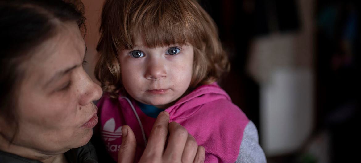 A mother holds her child in their apartment, in a partially destroyed high-rise building in eastern Ukraine.