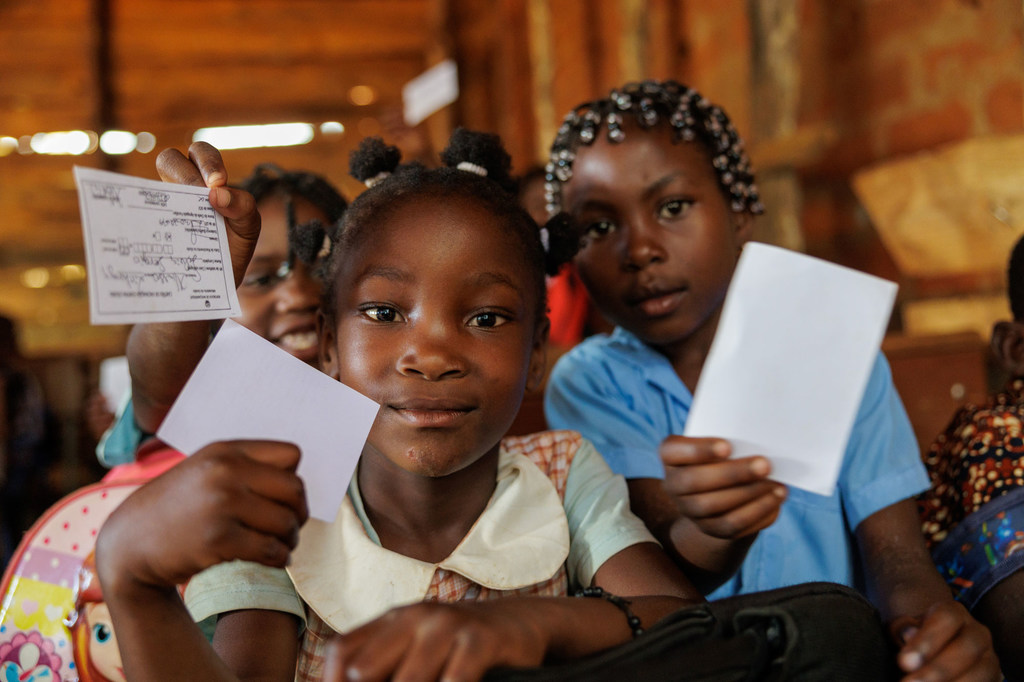 Meninas negras segurando cartões de vacinação após uma campanha de imunização contra a cólera em Lichinga, Moçambique.