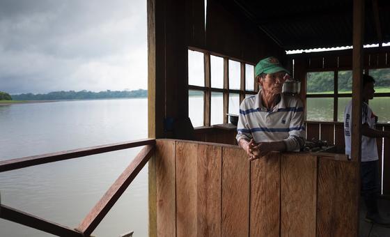 Um pescador em uma cabana de madeira na margem de um rio na Amazônia colombiana.
