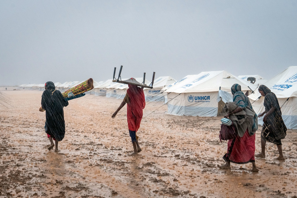 Des femmes déplacées transportent leurs effets personnels dans un site inondé, près de Kassala, au Soudan.