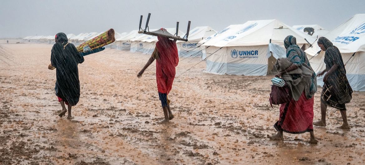 Des femmes déplacées transportent leurs effets personnels dans un site inondé, près de Kassala, au Soudan.