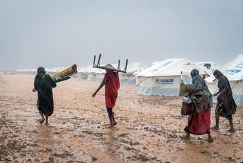 Displaced women carry their belongings through a flooded gathering site near Kassala, Sudan.