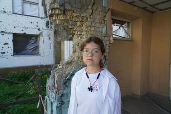 11-year-old Katya stands on the territory of the Irpin school, which was heavily bombed in March 2022.