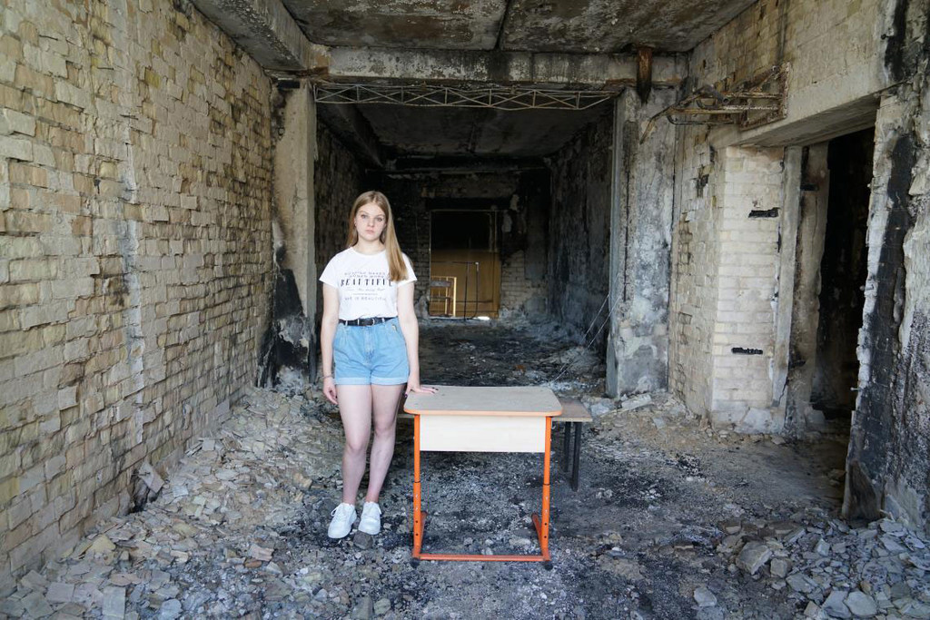 أرينا (15 عاما) تقف في مدرستها في إربين التي لحقت بها أضرار بالغة بسبب القصف في آذار/مارس 2022.