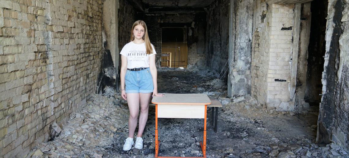 15 岁的阿丽娜站在乌克兰伊尔平学校的废墟上。她的学校在 2022 年 3 月遭到严重轰炸。