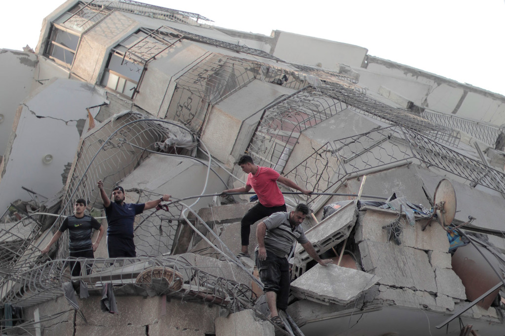 Un groupe d'hommes grimpe sur un bâtiment détruit à Gaza.