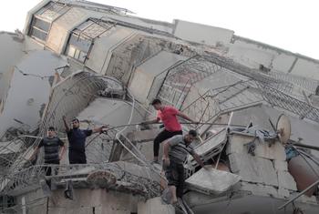 A group of men climb across a destroyed building in Gaza.