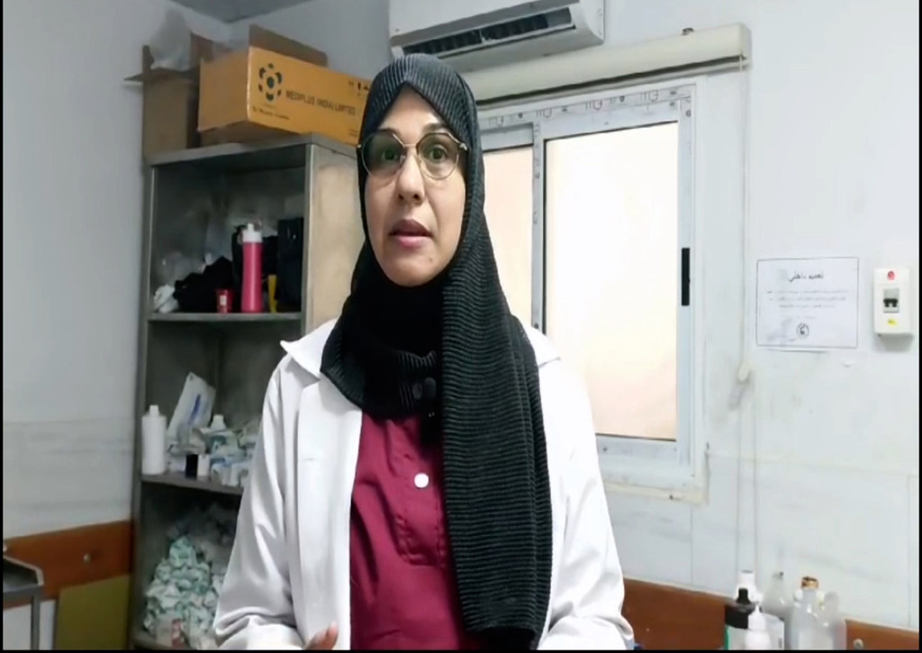 طبيبة فلسطينية ترتدي معطفاً أبيض وحجاباً تقف في غرفة طبية بمستشفى كمال عدوان في مخيم جباليا، شمال قطاع غزة.