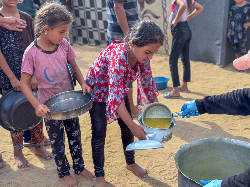 فتيات صغيرات يتلقين الطعام في مطبخ مجتمعي في دير البلح، غزة.