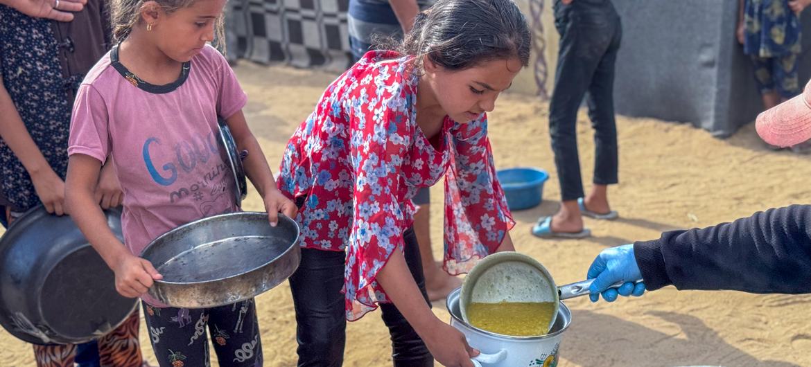 Meninas recebem comida em uma cozinha comunitária em Deir al Balah, Gaza