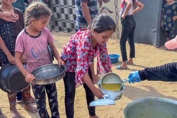 Meninas recebem comida em uma cozinha comunitária em Deir al Balah, Gaza