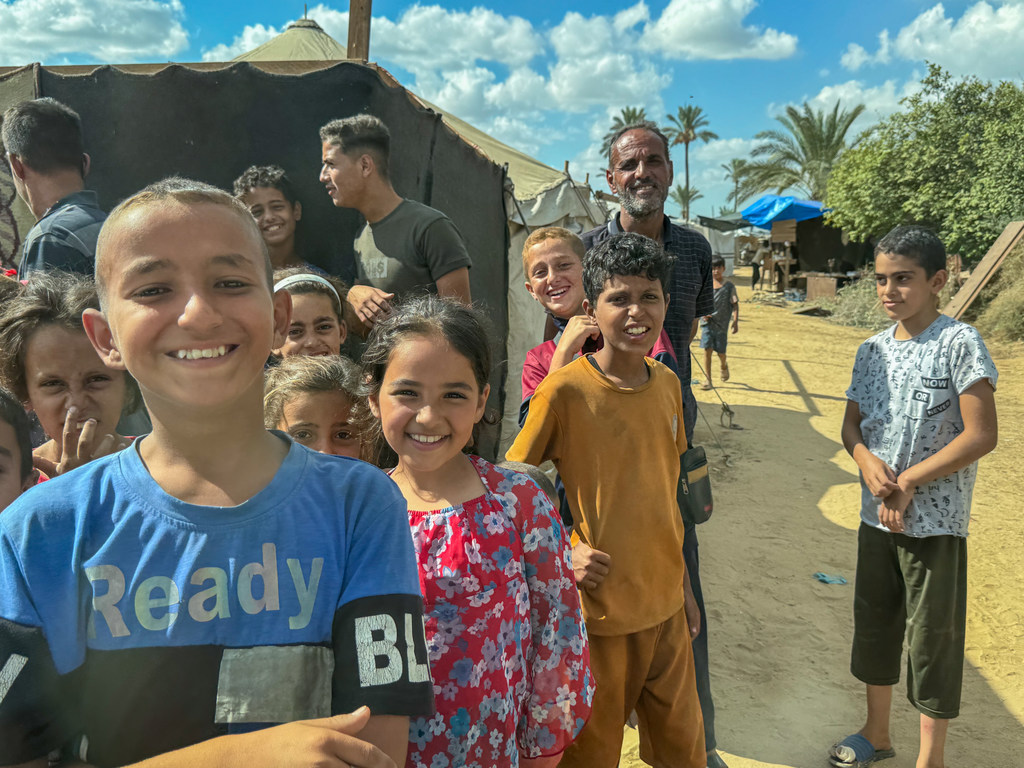 Niños desplazados y un hombre hacen fila en un comedor comunitario en Deir al Balah, Gaza, en octubre de 2025.