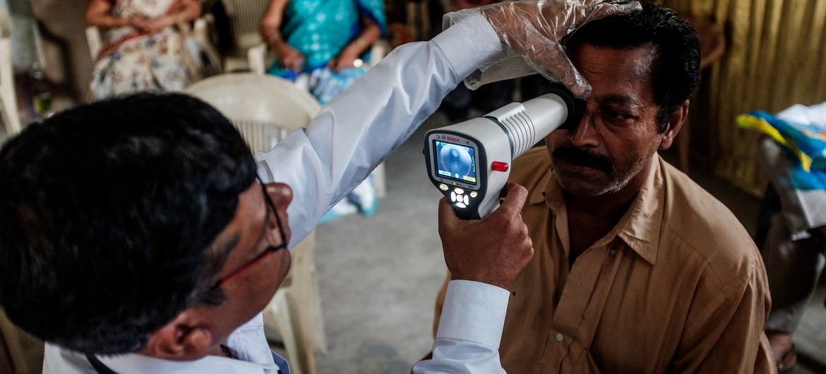 Un médico examina el ojo de un hombre con una lámpara de hendidura durante una prueba de detección de tracoma en la India.
