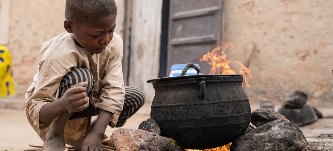 Un enfant aide sa màre à préparer le petit déjeuner au Niger