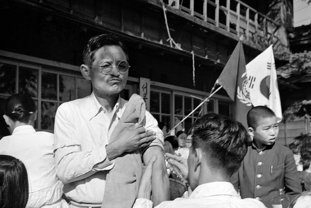 1950 में दक्षिण कोरिया के सियोल शहर में एक कोरियाई व्यक्ति को चेचक का टीका लगाया जा रहा है।