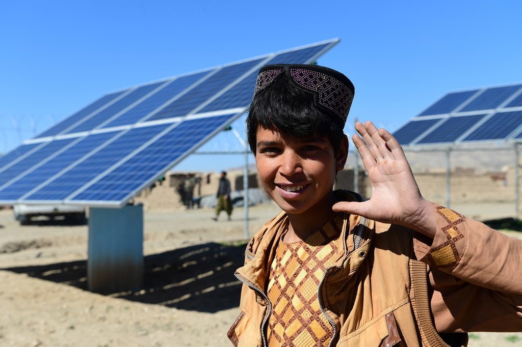 A boy stands in front of solar panels that provide electricity to pump water, in Herat, western Afghanistan. 