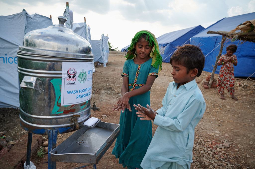 Fordrevne børn vasker deres hænder uden for et offentligt toilet i en lejr i Sindh-provinsen, Pakistan.
