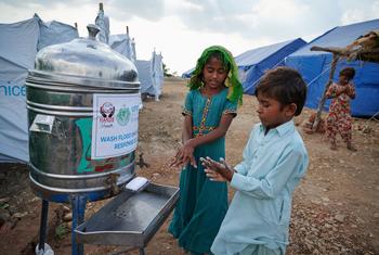 Niños desplazados se lavan las manos fuera de un baño público en un campamento en la provincia de Sindh, Pakistán.