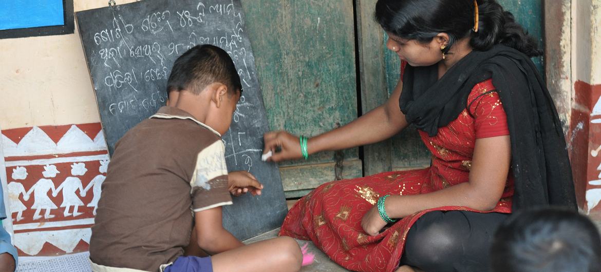 A volunteer for Pratham assists a student with reading in Orissa, India A volunteer for Pratham assists a student with reading in Orissa, India