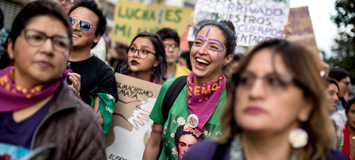 Mulheres e ativistas protestam no Equador contra a violência de gênero, exibindo cartazes com slogans em espanhol.