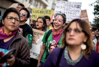Mulheres e ativistas protestam no Equador contra a violência de gênero, exibindo cartazes com slogans em espanhol.