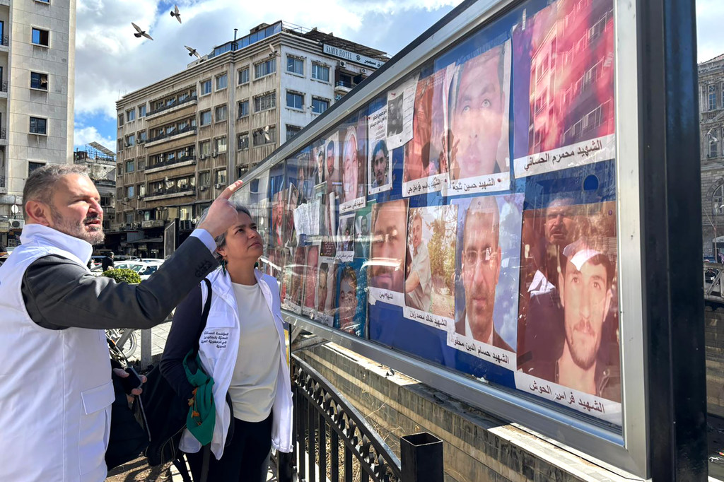 Karla Quintana (centro), directora de la Institución Independiente, visita la plaza Al Marjeh de Damasco, punto neurálgico donde las familias de los desaparecidos exponen fotos con la esperanza de encontrar a sus seres queridos.